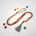 108-bead chakra mala with real gemstone beads in rainbow chakra colors draped in elegant loop on light grey background