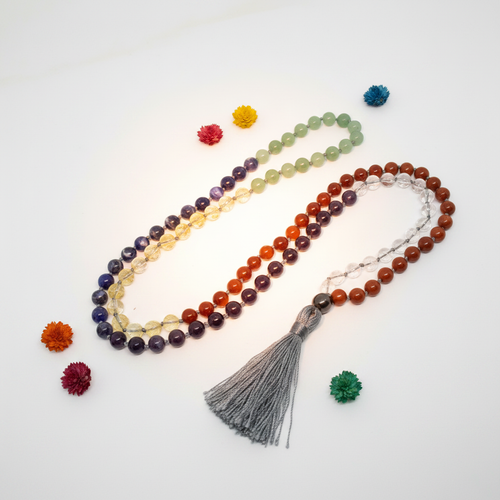 108-bead chakra mala with real gemstone beads in rainbow chakra colors draped in elegant loop on light grey background