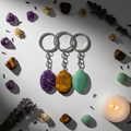 Flat lay of three crystal keychains with matching tumbled stones, dried flowers and candle