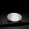 Selenite pillow stone with silky white pearlescent sheen on dark slate surface