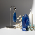 Blue Kyanite teardrop pendant with sterling silver diamond motif border on light grey background with raw crystals