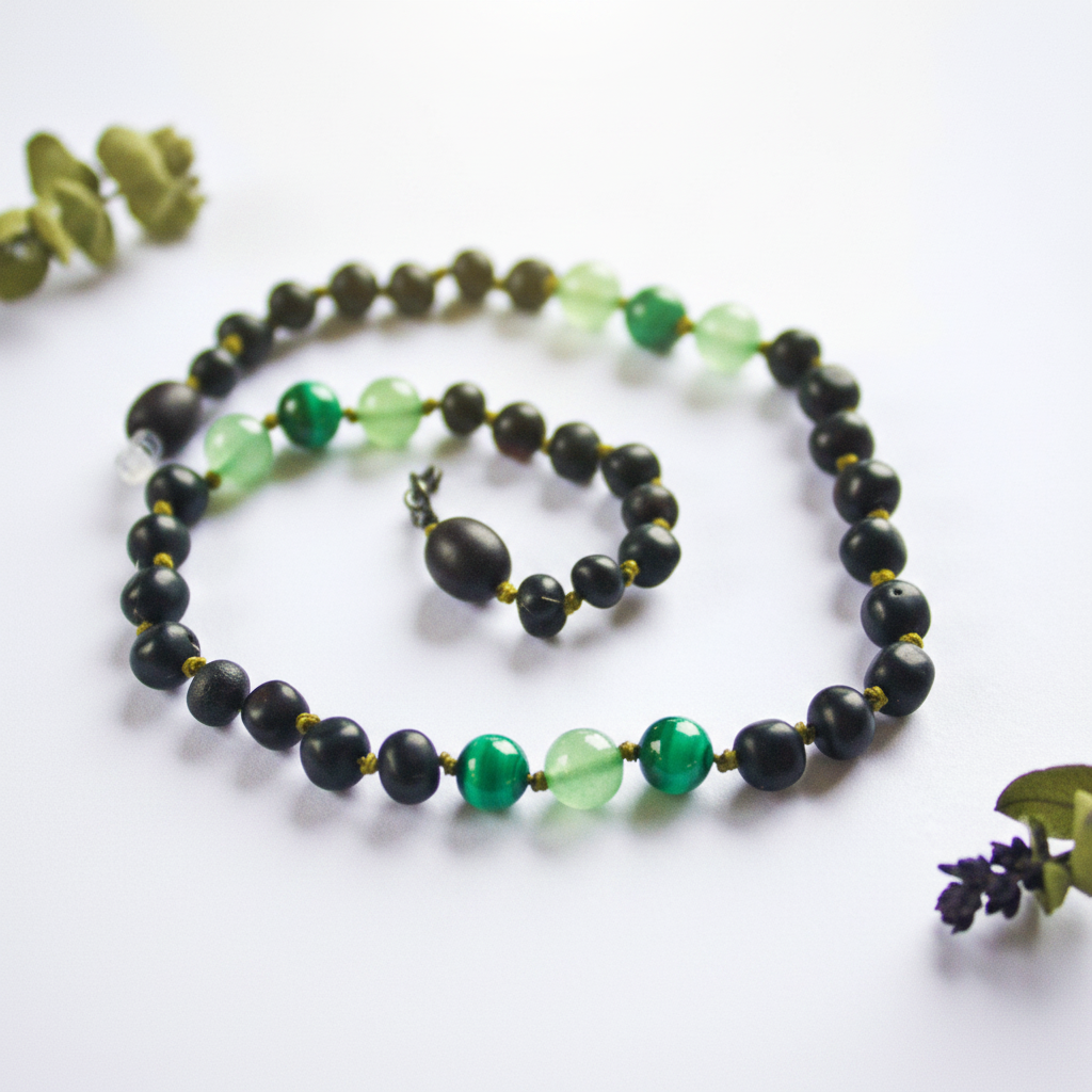 Raw molasses Baltic amber necklace with vivid green aventurine and malachite beads draped in elegant loop on light grey background