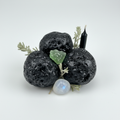 Raw Manitite tektite stones grouped with mugwort and moonstone on light grey background