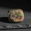 Tumbled Ocean Jasper purple dot crystal on dark slate surface