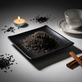 Loose leaf English Breakfast black tea on black ceramic plate with teacup and candle