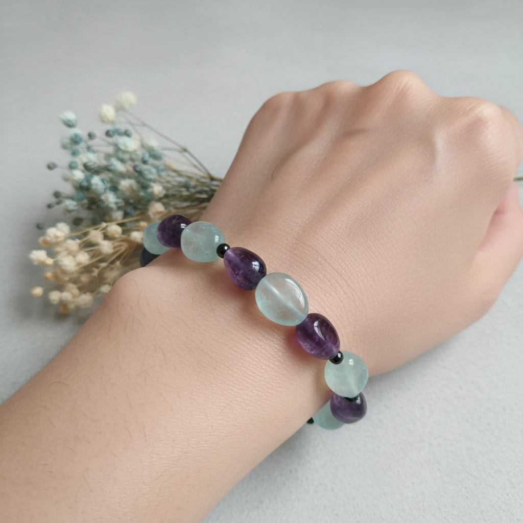 Natural fluorite bracelet worn on wrist showing pale aqua-blue tumbled nugget beads with dark round spacer beads