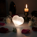 Selenite crystal heart with white flowers and candlelight