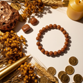 Goldstone 8mm beaded stretch bracelet with copper chunk, golden botanicals and gold coins on light grey background