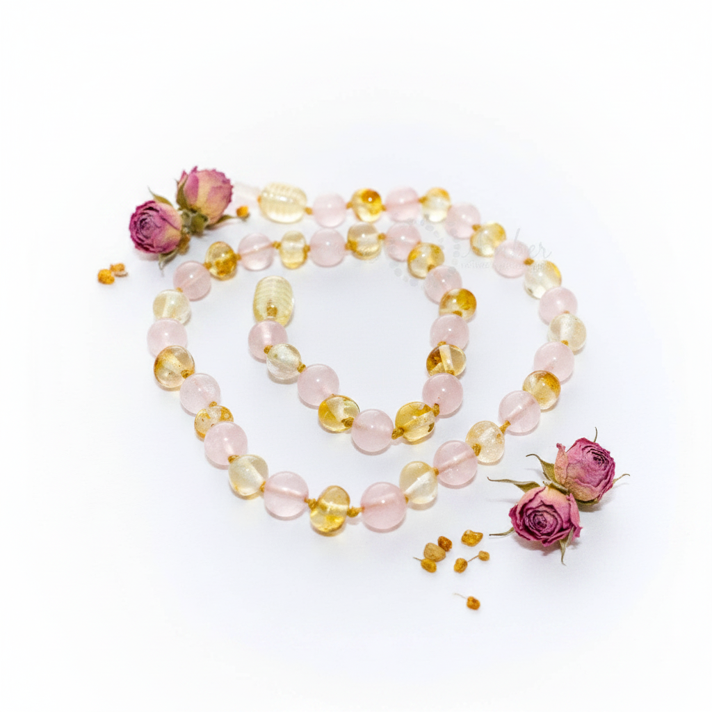 Baltic amber and rose quartz necklace with alternating warm gold and soft blush pink beads draped in elegant loop on light grey background