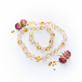 Baltic amber and rose quartz necklace with alternating warm gold and soft blush pink beads draped in elegant loop on light grey background