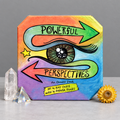 Powerful Perspectives oracle deck in a grey studio setting with quartz, prism and yellow flower