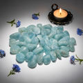 Cluster of aquamarine tumbled stones with blue flowers and candle props