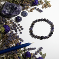 Iolite gemstone 8mm beaded stretch bracelet with raw iolite, lavender and blue taper candle on light grey background